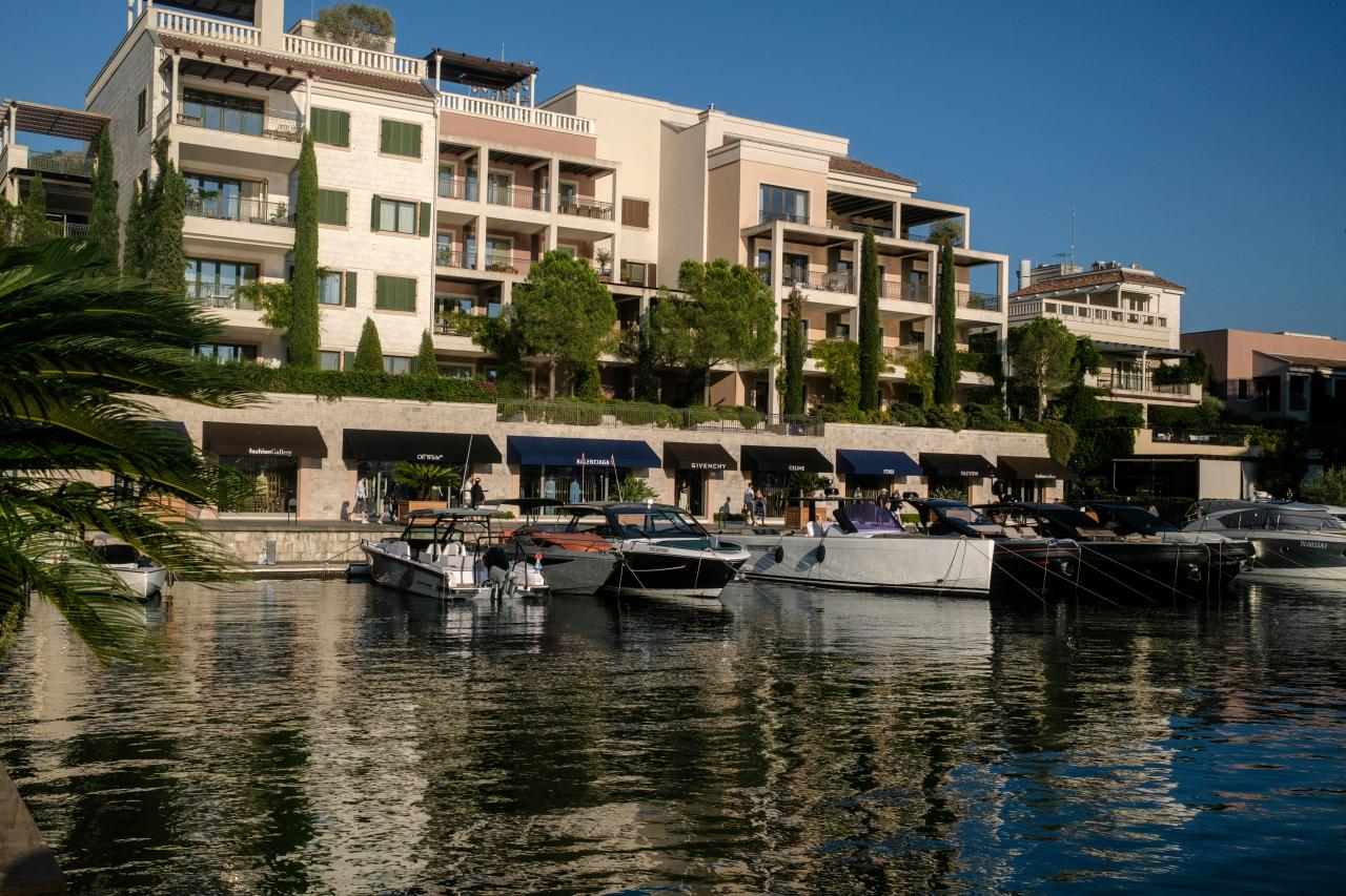 Modern buildings line a marina with docked boats.