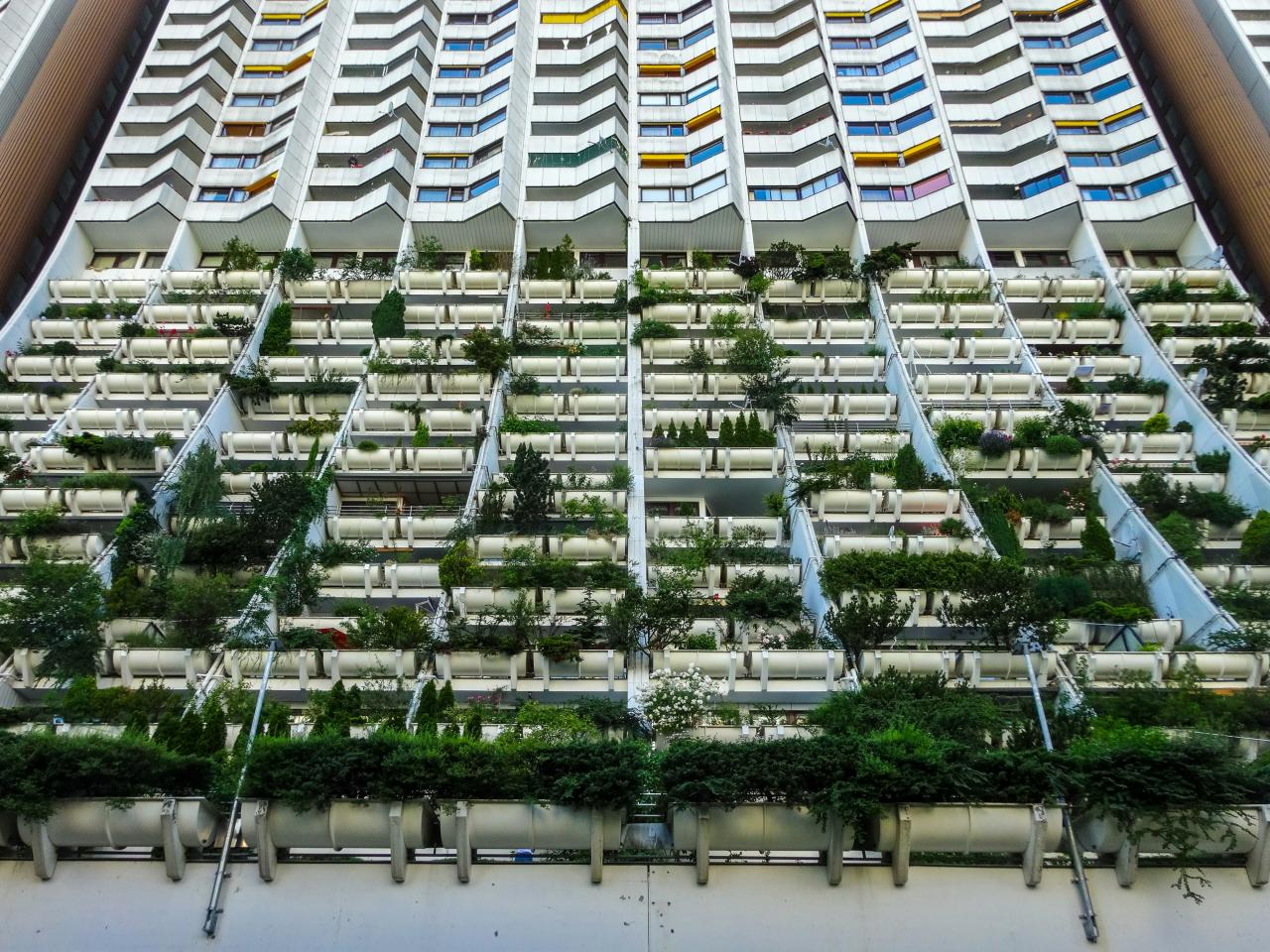Apartment building with many balconies filled with plants.