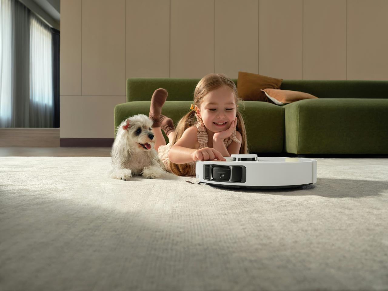 Girl and dog watch robot vacuum cleaner